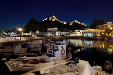 The old port of Myrina on the island of Limnos with the illuminated Venetian Castle in the...