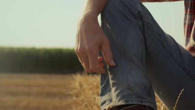 Man leg haystack bale at countryside closeup. Unknown farmer resting straw roll