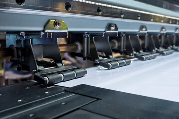 Closeup of a large format tarpaulin printer, showing the anti-static pinch rollers and mute guide...