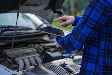 A young man checks his car and repairs it before going on a long journey.