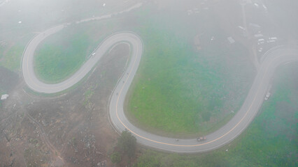 Aerial drone top view of a road curve winding through the mountains.