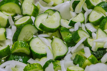 Fresh cucumber, sliced and sliced mixed with onions in a bowl. Preparation of vegetables for marinade. A fresh crop of vegetables. Salad with cucumber and onion. 