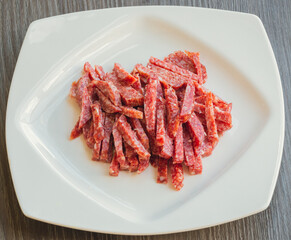 Lots of Spanish Serrano ham and Spanish sausage, festive, Iberian pork loin on a white platter. Smoked sausage cut into small slices in a white plate close-up selective focus.  Meat products.