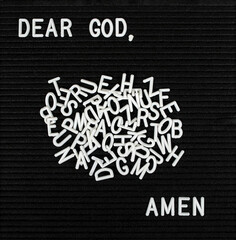 Prayer with scattered plastic white letters on a black felt bulletin board 