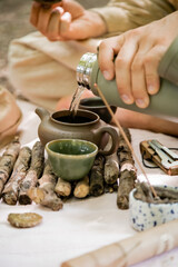 Cropped view of man pouring hot water in teapot during tea ceremony in forest.