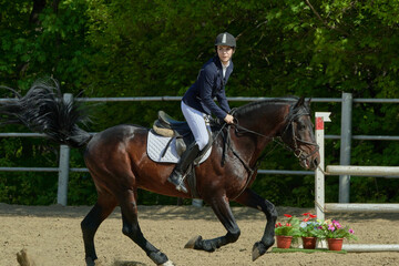 A young woman performs a sports race on a horse on a sunny summer day.