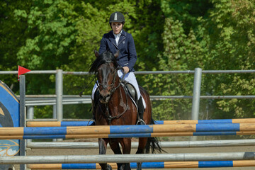 A young woman performs a sports race on a horse on a sunny summer day.