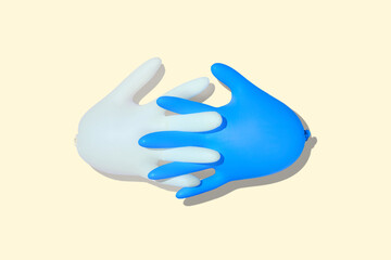 Inflated medical gloves. A pair of protective gloves with interlocked fingers. Latex blue and white gloves on yellow background. Close-up.