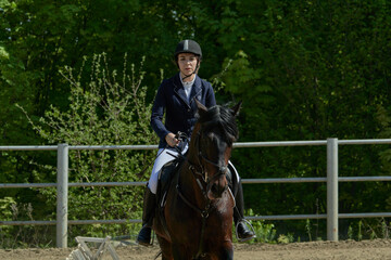 A young woman is preparing for a sports race on a horse on a sunny summer day.