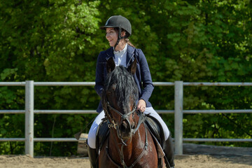 A young woman finished a sports race on a horse on a sunny summer day.