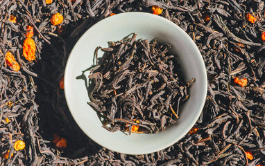 Green tea with berries in a bowl on the background of scattered tea. Ivan tea with sea buckthorn in...
