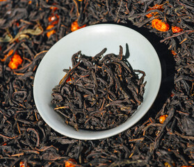 Green tea with berries in a bowl on the background of scattered tea. Ivan tea with sea buckthorn in...