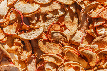 Background of dried apple slices. Dried slices of apples finely chopped for the preparation of healthy drinks, fruit drinks and compotes. Dried apple chips background selective focus top view.