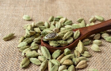 Closeup of Cardamon Pod or Cardamom in Wooden Spoon on Isolated on Burlap Fabric in Horizontal Orientation