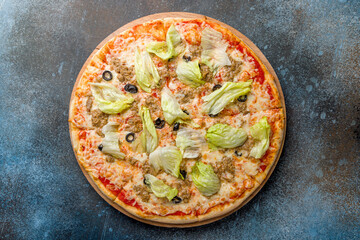 Pizza with tuna and green salad with cheese and tomato sauce top view on dark blue stone table