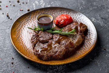 juicy Ribeye steak on brown plate with pepper sauce