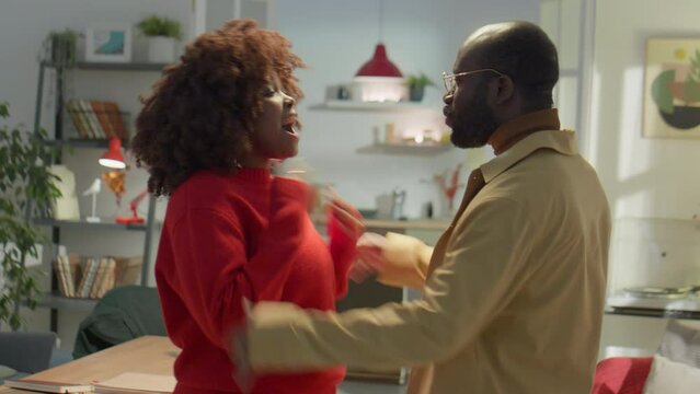 Waist up shot of hysterical African American wife and husband standing at home and blaming each other while having emotional dispute
