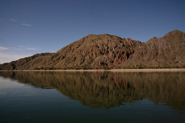Symmetry in nature. Panorama view of the arid mountains and blue sky reflection in the lake.