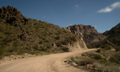 Travel. View of the dirt road across the arid desert and colorful rock formations.