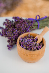Obraz na płótnie Canvas Wooden bowl with dried lavender on field background. Flower herbal tea drink. Aromatherapy, medicine ingredient. Calming beverage