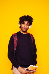 Young handsome african american guy student posing cheerful and gesturing on yellow background, lifestyle people concept