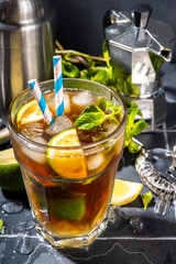 Lavazza mojito mocktail. Strong black espresso coffee cold drink with mojito cocktail, lime, lemon, mint leaves, trendy summer iced beverage on dark background copy pace