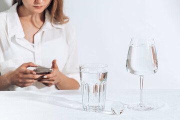 Casual style young woman texting on a smartphone. water glasses. Female model