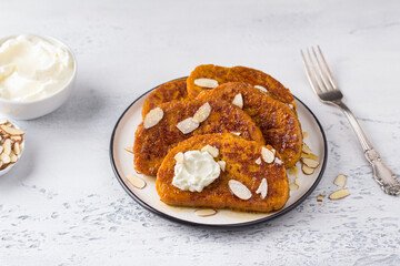 Sweet pumpkin toast with honey and cream, sprinkled with powdered sugar and almond petals on a light blue textured background. Delicious homemade breakfast - 518149637