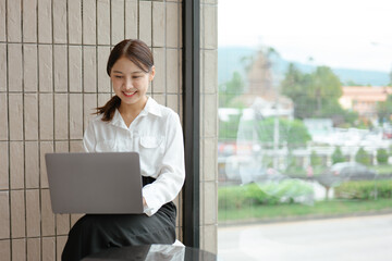 Young business women working and typing on laptop with happy and smile face on office spec.