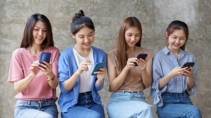 Beautiful young Asian woman using smartphone in the office during her break.