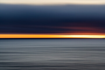 A cloudy sunset over the ocean turned into colorful and grey streaks