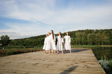 Gentle dance number performed by five girls in white dresses against the background of the lake