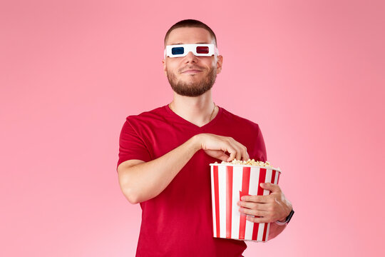 Young caucasian man in 3d glasses eating popcorn