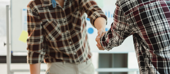 Young start up businessman and woman shaking hands in the office working together as a team.
