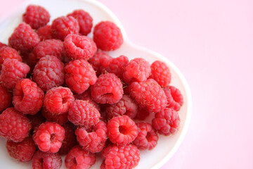 large ripe raspberries on a pink background