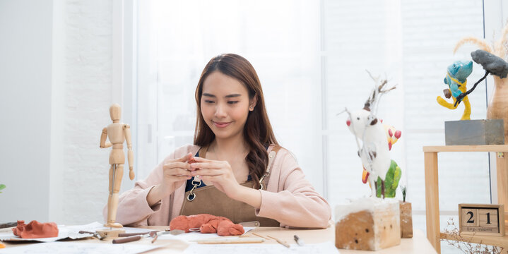Young Asian girl making a sculpture with modeling clay at home .hobby clay sculpt concept