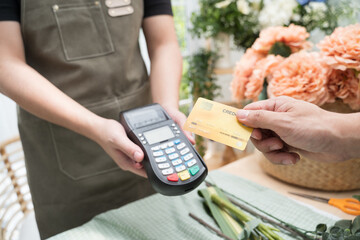 Hand of customer paying with contactless credit card in flower shop