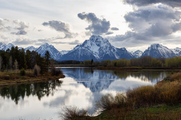 Fototapeta na wymiar River surrounded by Trees and Mountains in American Landscape. Snake River, Oxbow Bend. Spring Season. Grand Teton National Park. Wyoming, United States. Nature Background.