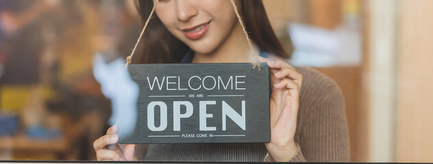 beautiful female business retail owner  hanging open wooden sign board at the entrance door of the...