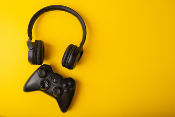 Headphones and joystick on a yellow background. Video game concept