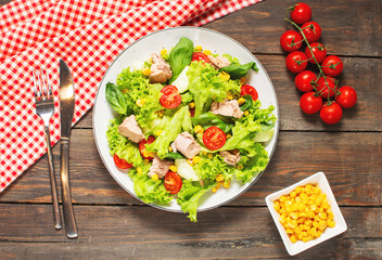 Tuna Fish Salad with Lettuce, Cherry Tomatoes, Cucumber and Corn on wooden background