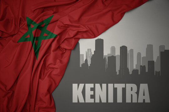 abstract silhouette of the city with text Kenitra near waving colorful national flag of morocco on a gray background.