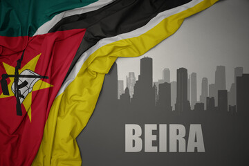 abstract silhouette of the city with text Beira near waving colorful national flag of mozambique on...