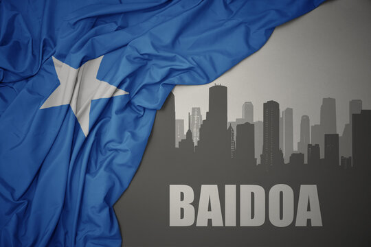 abstract silhouette of the city with text Baidoa near waving colorful national flag of somalia on a gray background.
