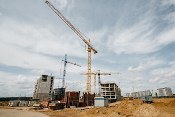 cranes at the construction site of stylish houses against the blue sky