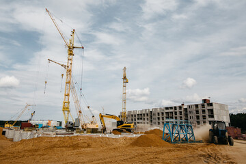cranes at the construction site of stylish houses against the blue sky
