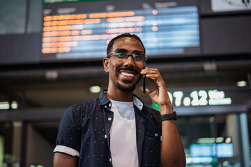 African male talking on the phone while he waits at a train station