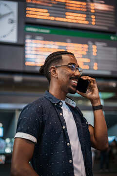 African man making a call with a friend while he is waiting at a train station