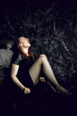 Obraz na płótnie Canvas Young redhead woman sitting on floor near bed and screaming. Mental health, depression, pain, despair.
