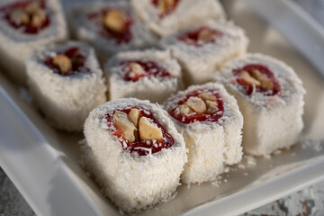 Turkish delight with strawberry jam, nuts and coconut flakes on a white plate